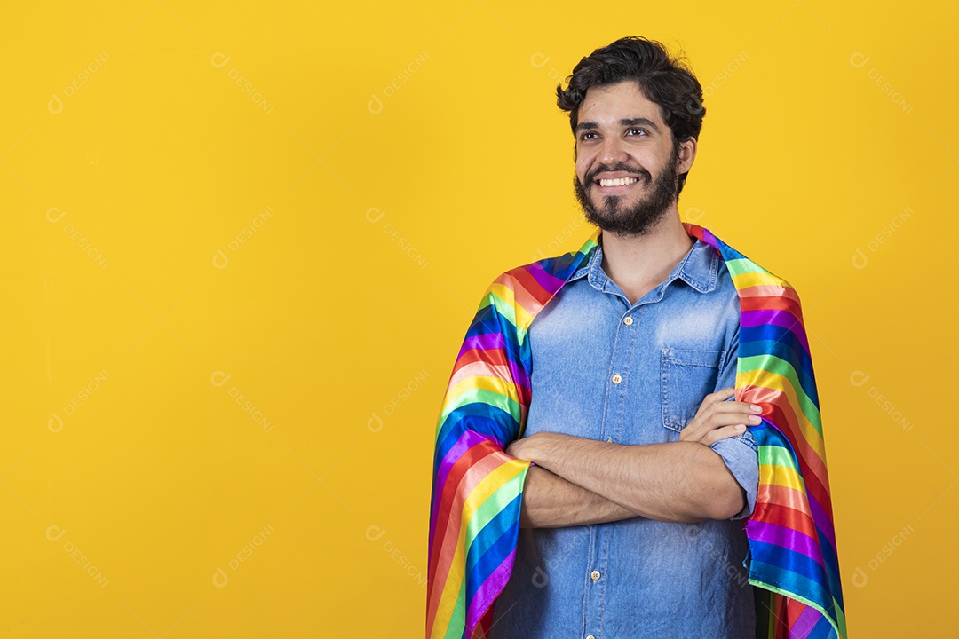 Homem jovem segurando bandeira LGBT barbudo sobre fundo amarelo