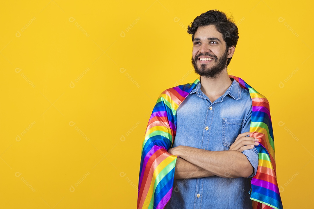 Homem jovem segurando bandeira LGBT barbudo sobre fundo amarelo