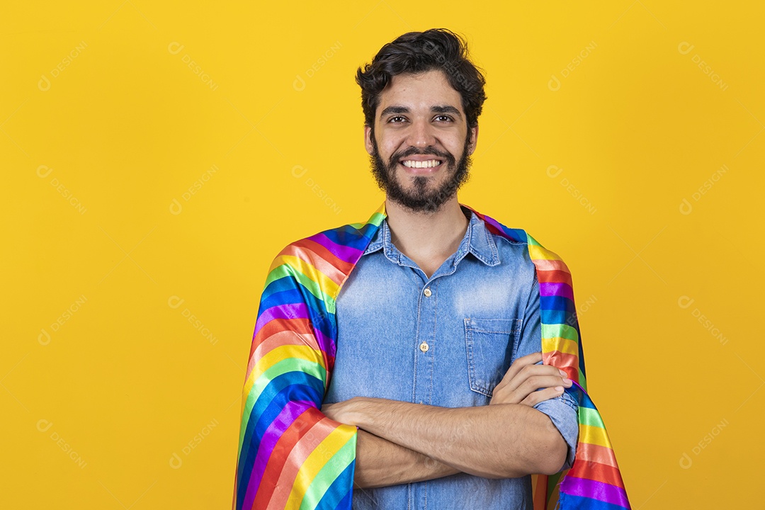 Homem jovem segurando bandeira LGBT barbudo sobre fundo amarelo