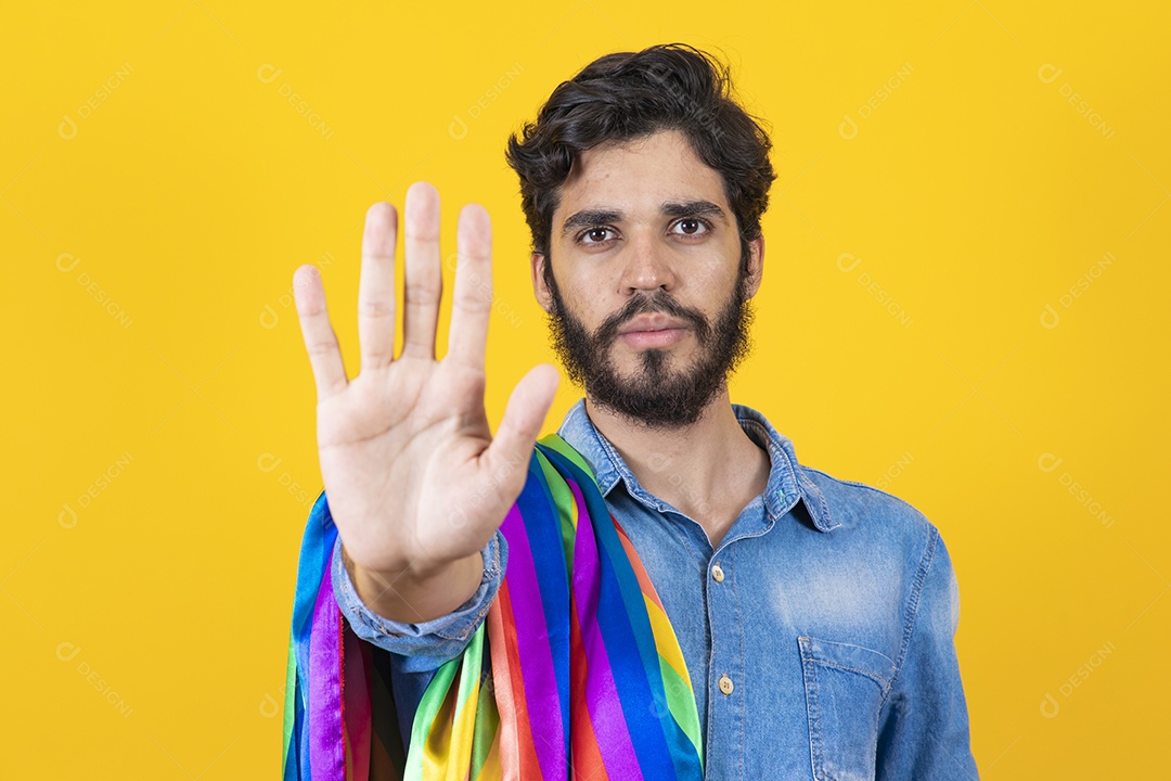 Homem jovem segurando bandeira LGBT barbudo sobre fundo amarelo