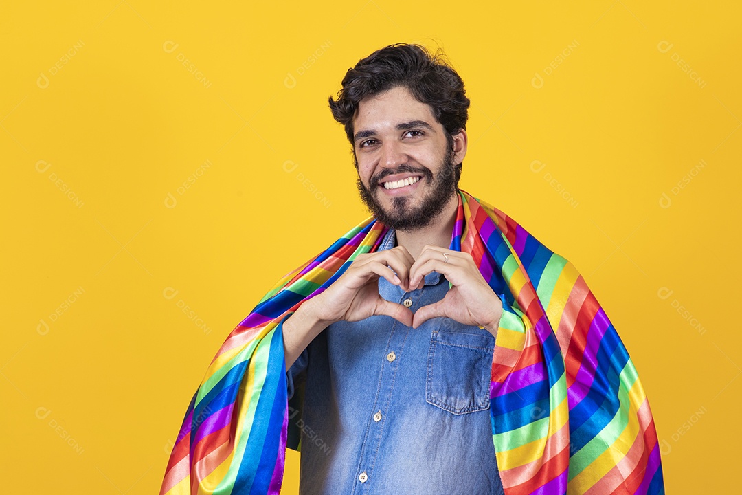 Homem jovem segurando bandeira LGBT barbudo sobre fundo amarelo