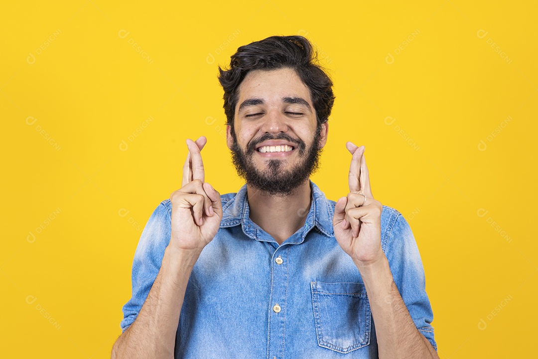 Homem jovem barbudo dedos cruzados sobre fundo amarelo