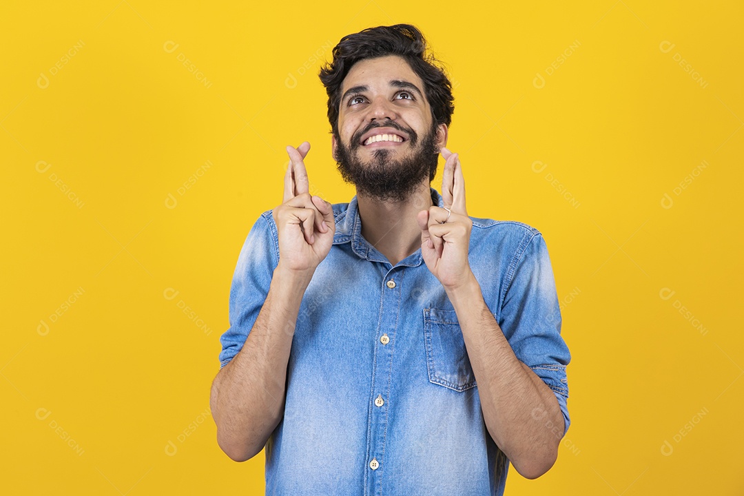 Homem jovem barbudo dedos cruzados sobre fundo amarelo