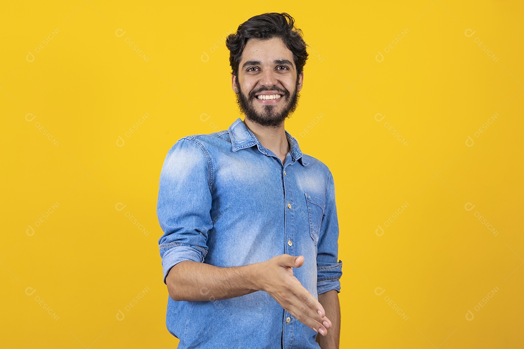 Homem jovem barbudo dando sua mão para outra pessoa aperta sobre fundo amarelo
