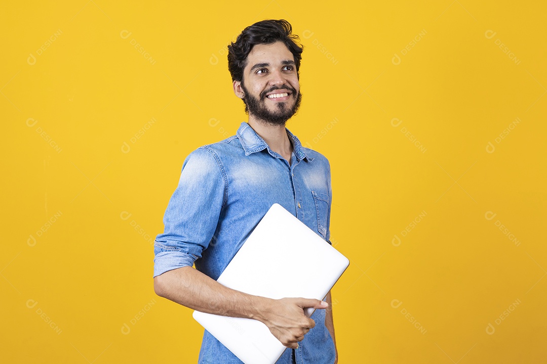 Homem jovem segurando notebook barbudo sobre fundo amarelo