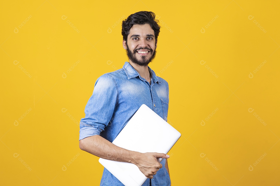 Homem jovem segurando notebook barbudo sobre fundo amarelo