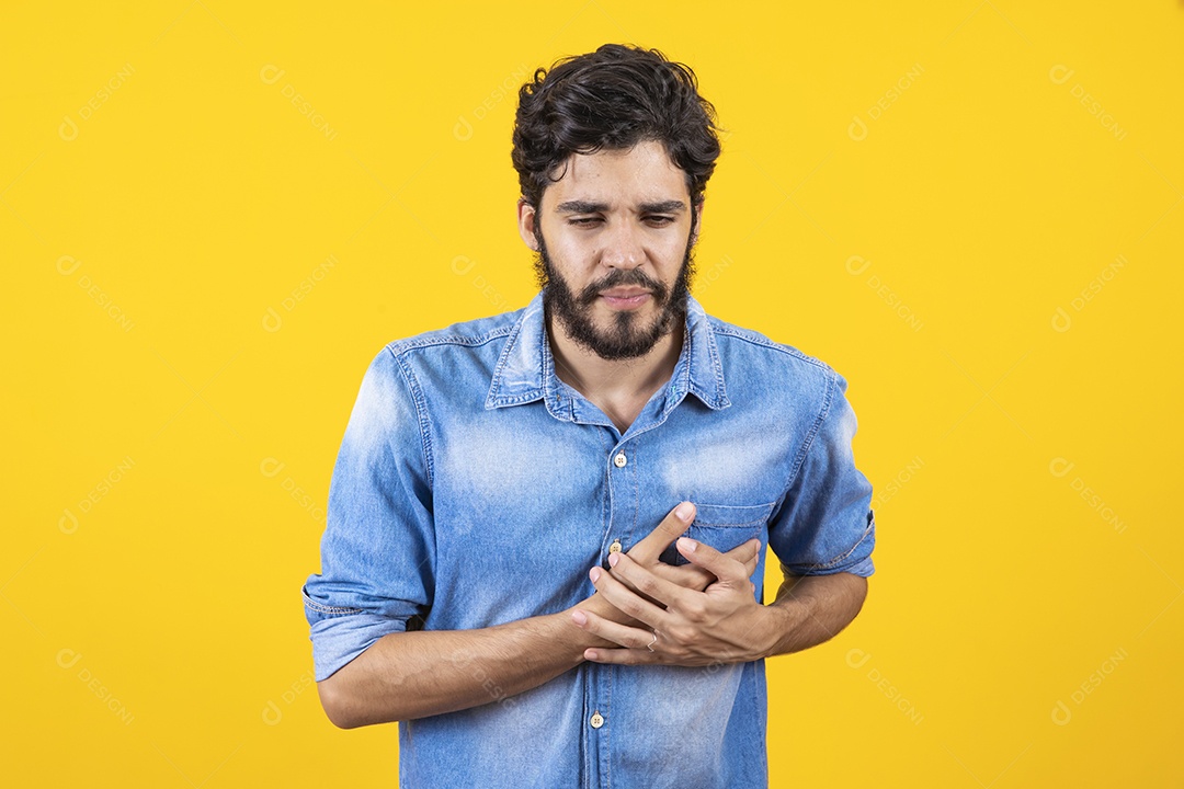 Homem jovem sentindo dor no peito barbudo sobre fundo amarelo
