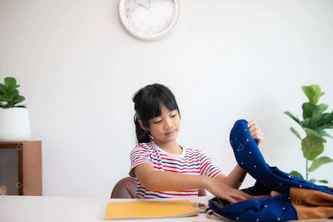 Menina asiática bonita da escola primária arrumando suas mochilas escolares, preparando-se para o primeiro dia de aula