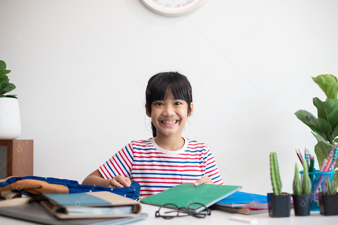 Menina asiática bonita da escola primária arrumando suas mochilas escolares, preparando-se para o primeiro dia de aula
