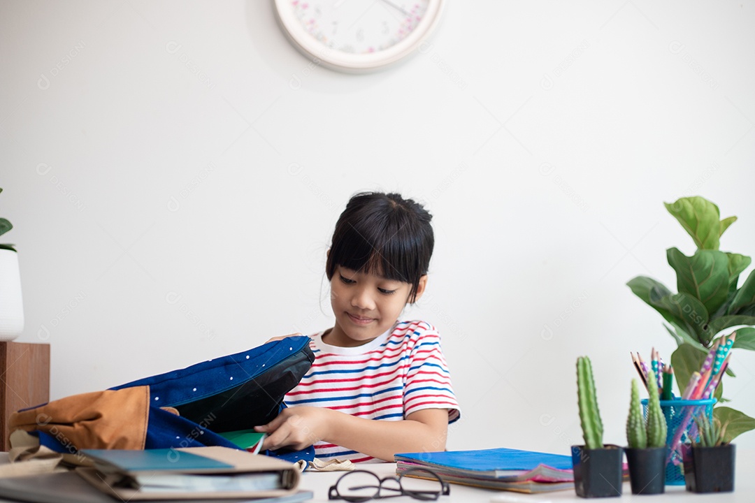 Menina asiática bonita da escola primária arrumando suas mochilas escolares, preparando-se para o primeiro dia de aula