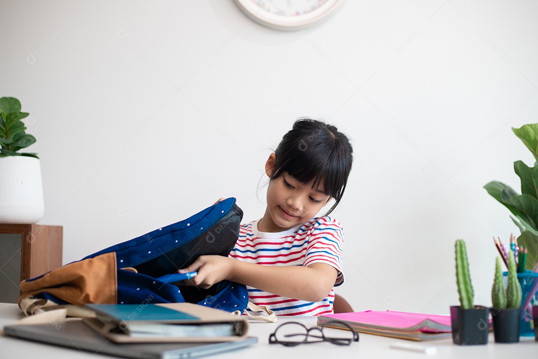 Menina asiática bonita da escola primária arrumando suas mochilas escolares, preparando-se para o primeiro dia de aula