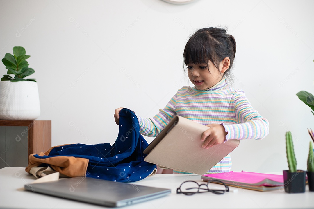 Menina asiática bonita da escola primária arrumando suas mochilas escolares, preparando-se para o primeiro dia de aula