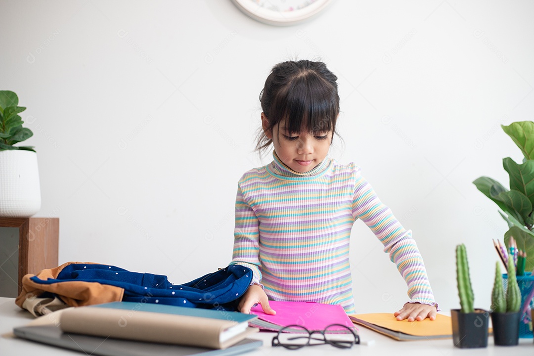Menina asiática bonita da escola primária arrumando suas mochilas escolares, preparando-se para o primeiro dia de aula