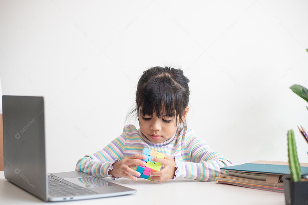 Menina asiática bonita segurando o cubo de Rubik em suas mãos. O cubo de Rubik é um jogo que aumenta a inteligência das crianças.
