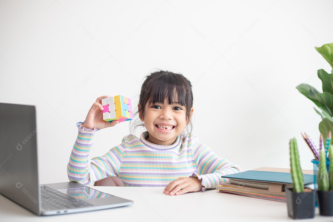 Menina asiática bonita segurando o cubo de Rubik em suas mãos. O cubo de Rubik é um jogo que aumenta a inteligência das crianças.