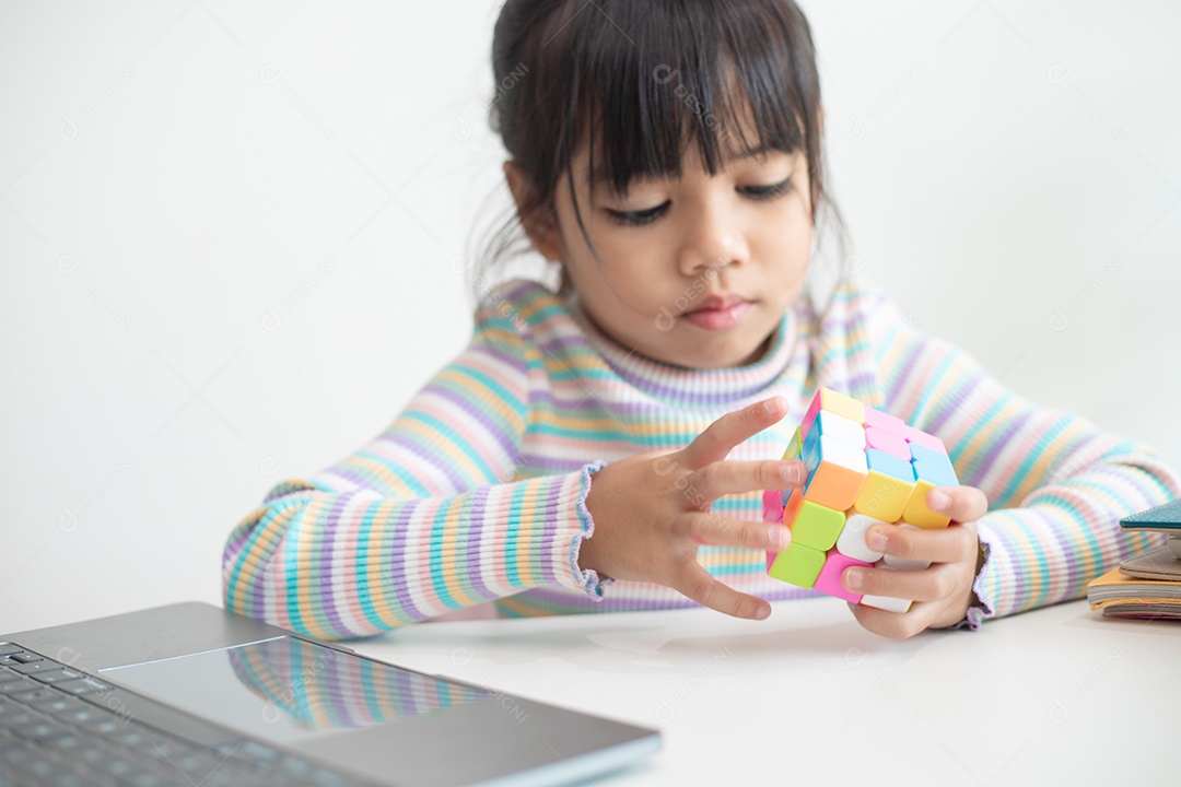 Menina asiática bonita segurando o cubo de Rubik em suas mãos. O cubo de Rubik é um jogo que aumenta a inteligência das crianças.