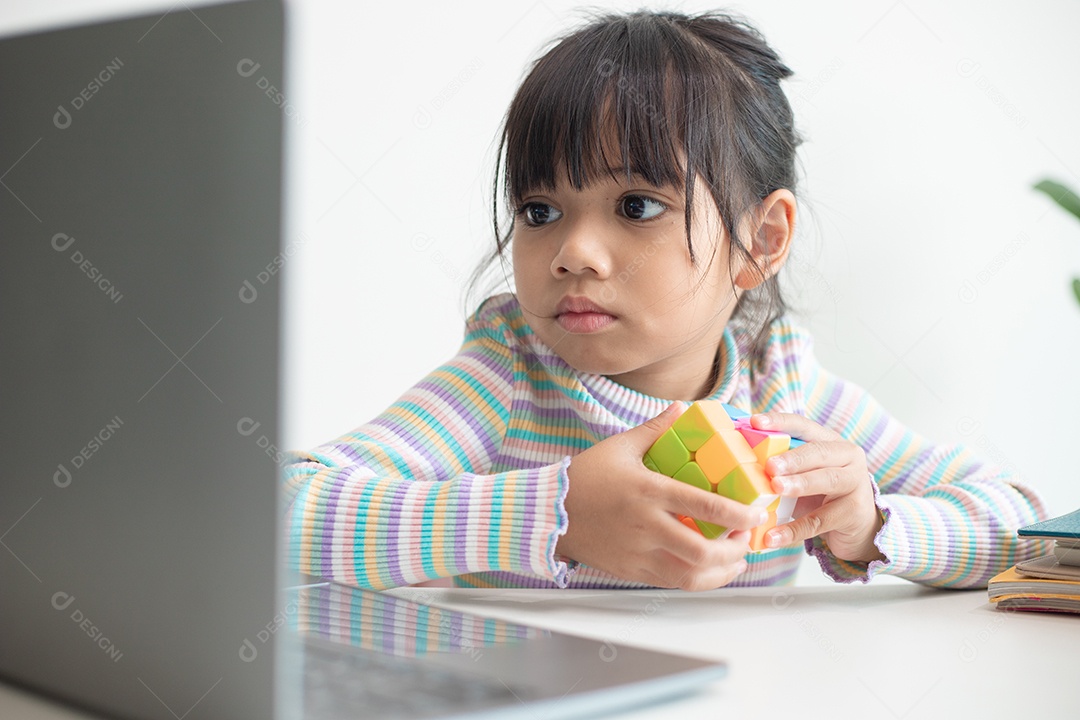 Menina asiática bonita segurando o cubo de Rubik em suas mãos. O cubo de Rubik é um jogo que aumenta a inteligência das crianças.