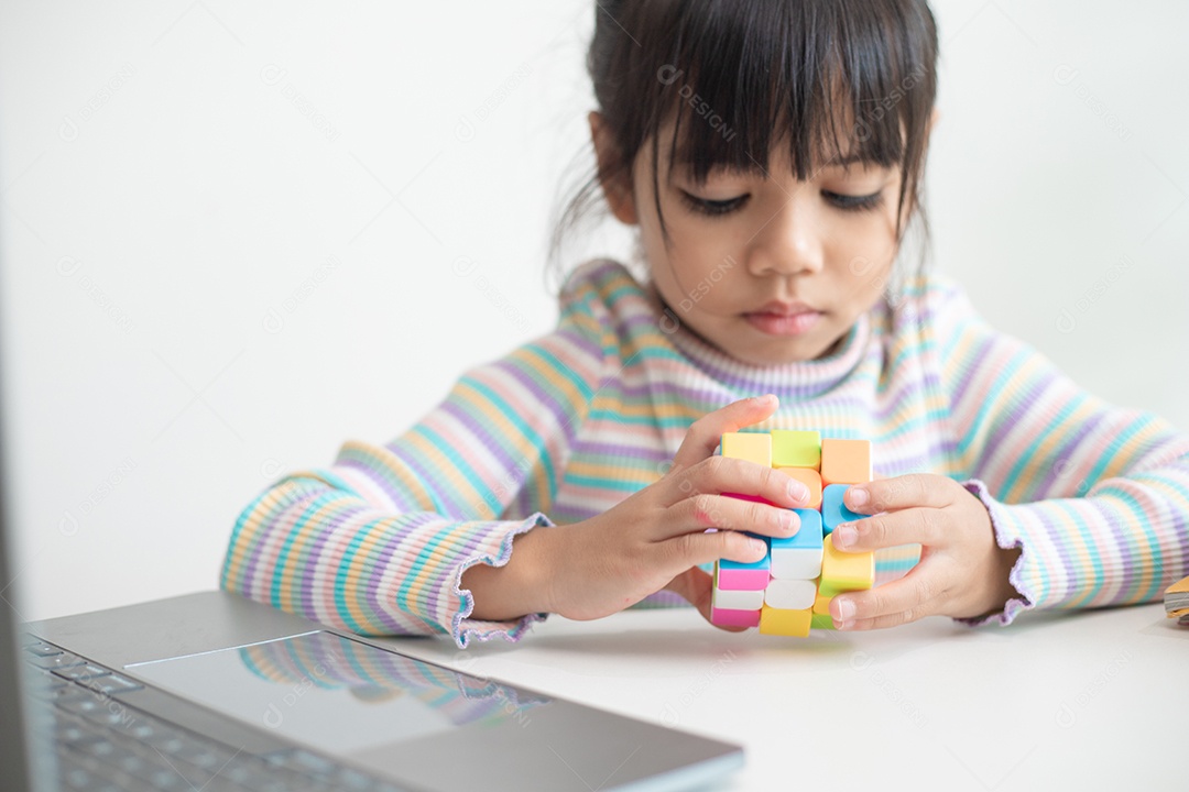 Menina asiática bonita segurando o cubo de Rubik em suas mãos. O cubo de Rubik é um jogo que aumenta a inteligência das crianças.