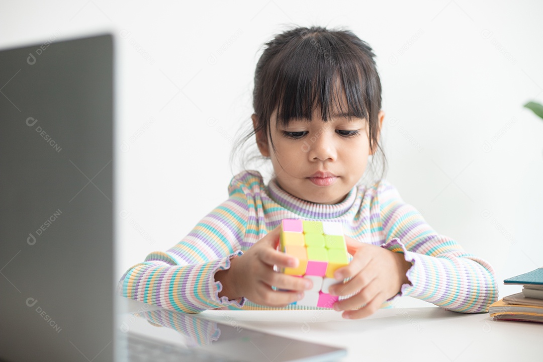 Menina asiática bonita segurando o cubo de Rubik em suas mãos. O cubo de Rubik é um jogo que aumenta a inteligência das crianças.