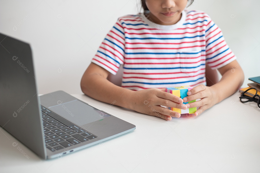 Menina asiática bonita segurando o cubo de Rubik em suas mãos. O cubo de Rubik é um jogo que aumenta a inteligência das crianças.