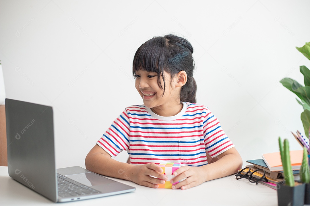 Menina asiática bonita segurando o cubo de Rubik em suas mãos. O cubo de Rubik é um jogo que aumenta a inteligência das crianças.