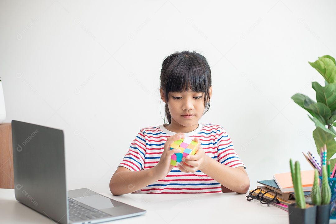 Menina asiática bonita segurando o cubo de Rubik em suas mãos. O cubo de Rubik é um jogo que aumenta a inteligência das crianças.