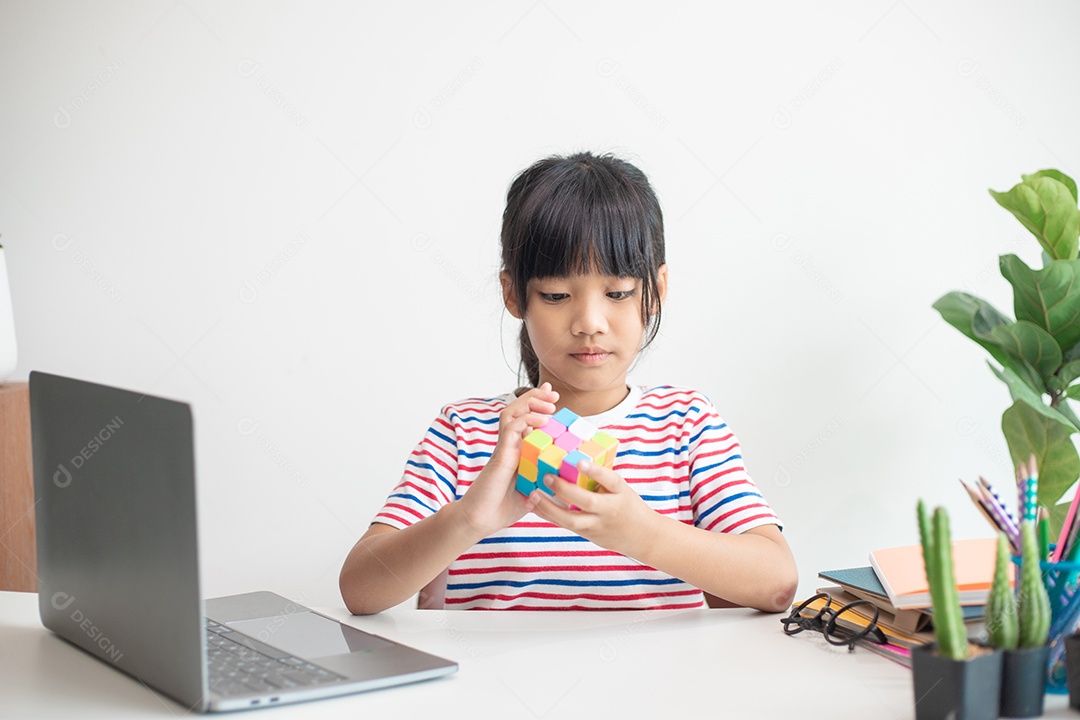 Menina asiática bonita segurando o cubo de Rubik em suas mãos. O cubo de Rubik é um jogo que aumenta a inteligência das crianças.