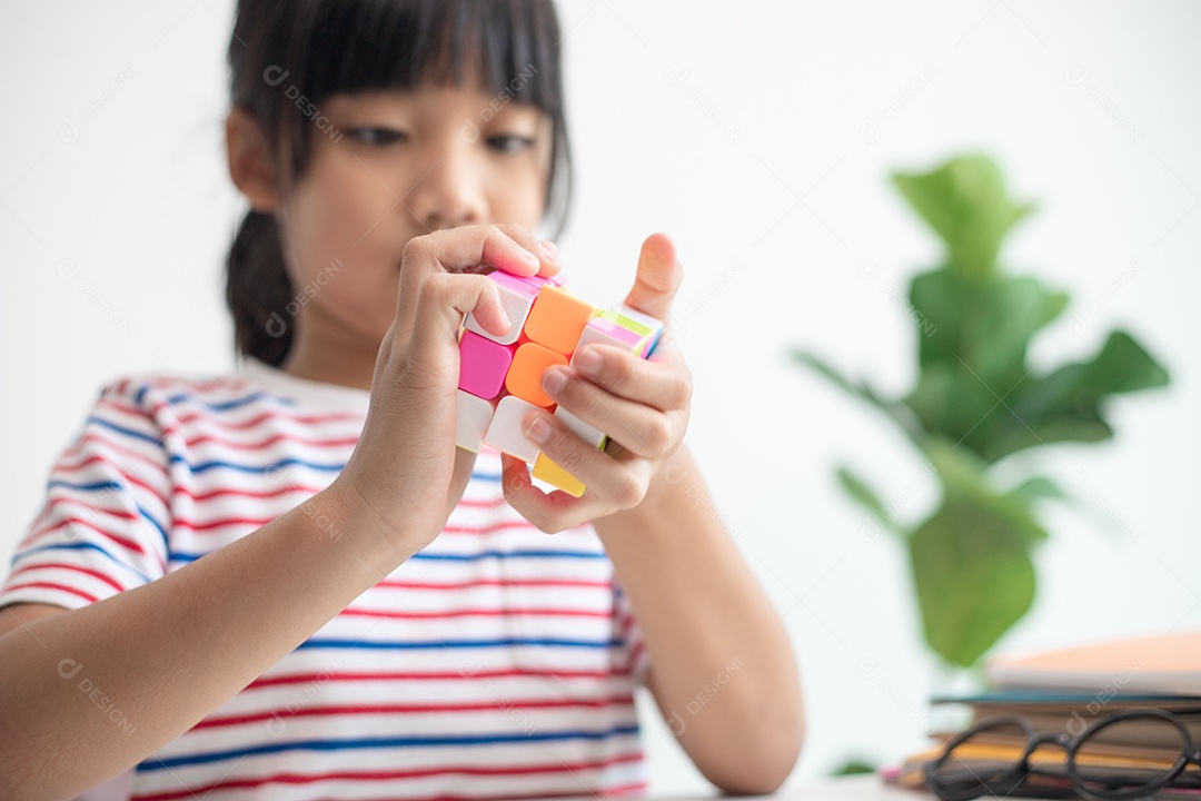Menina asiática bonita segurando o cubo de Rubik em suas mãos. O cubo de Rubik é um jogo que aumenta a inteligência das crianças.