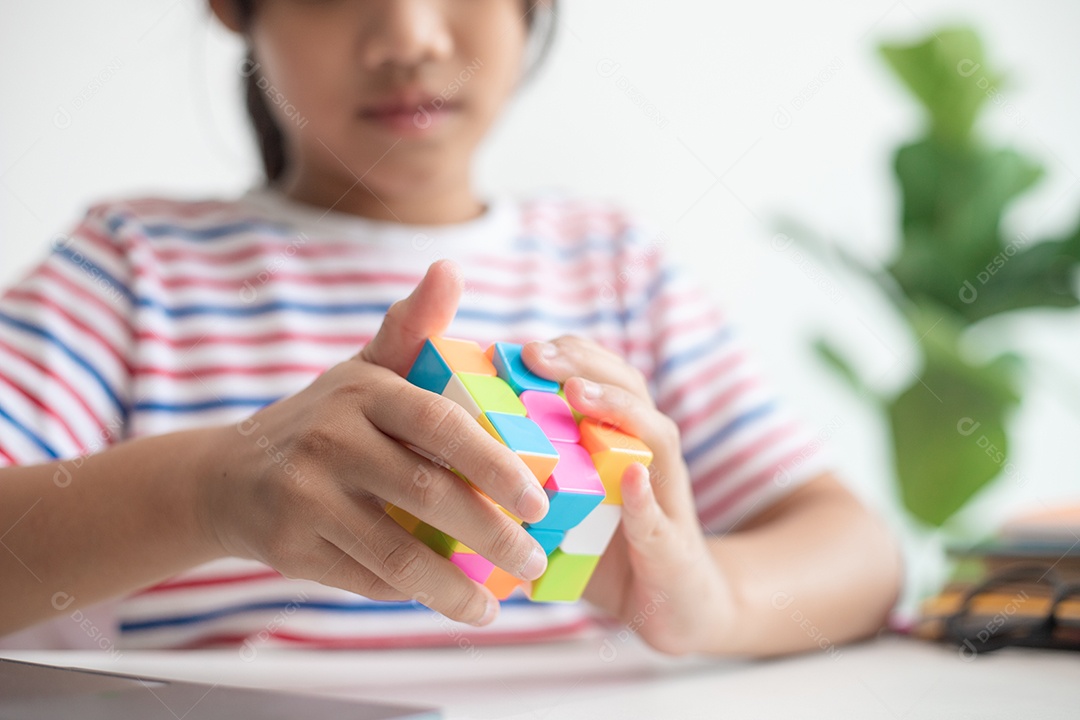 Menina asiática bonita segurando o cubo de Rubik em suas mãos. O cubo de Rubik é um jogo que aumenta a inteligência das crianças.
