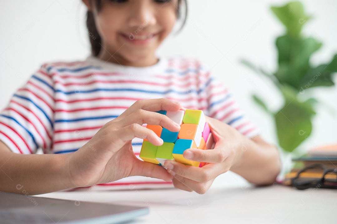 Menina asiática bonita segurando o cubo de Rubik em suas mãos. O cubo de Rubik é um jogo que aumenta a inteligência das crianças.