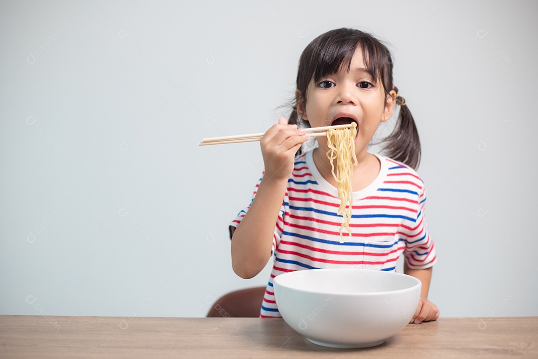 Linda garota asiática comendo deliciosos macarrão instantâneo em casa.