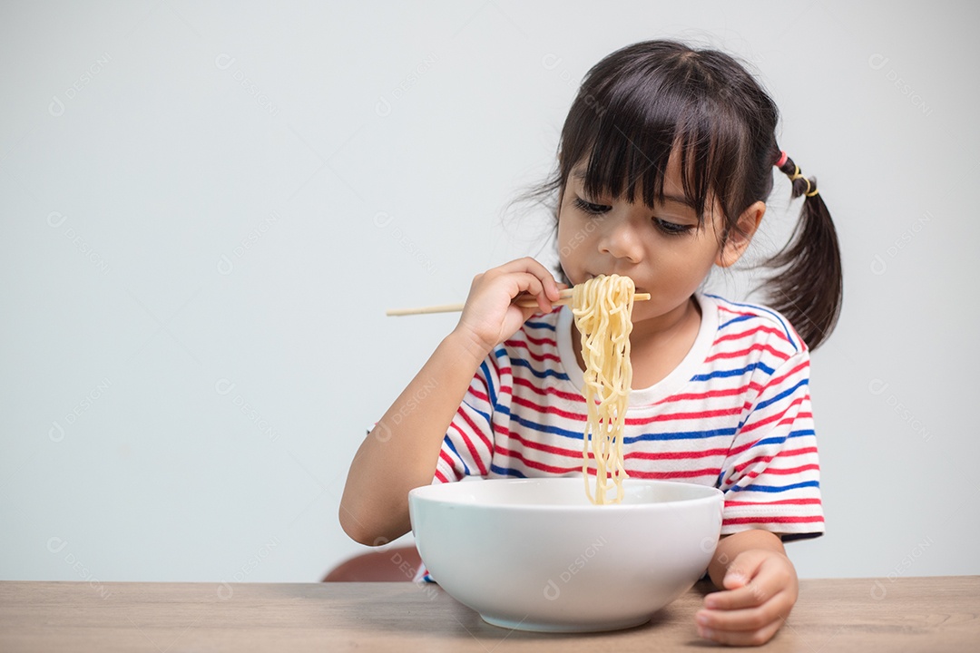 Linda garota asiática comendo deliciosos macarrão instantâneo em casa.