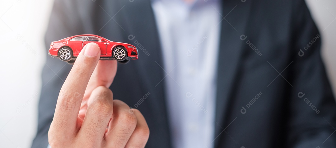 Mão de empresário segurando o brinquedo do carro vermelho. Seguro de carro, garantia, aluguel, financeiro, novo e conceito de reparo