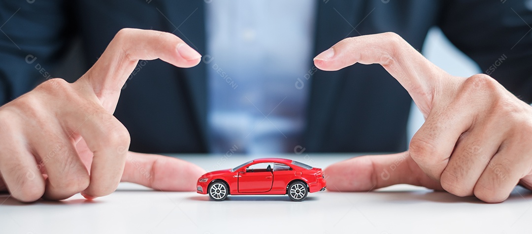 Capa de mão de empresário ou brinquedo de carro vermelho de proteção na mesa. Seguro automóvel, garantia, reparação, financeiro, bancário e conceito de dinheiro
