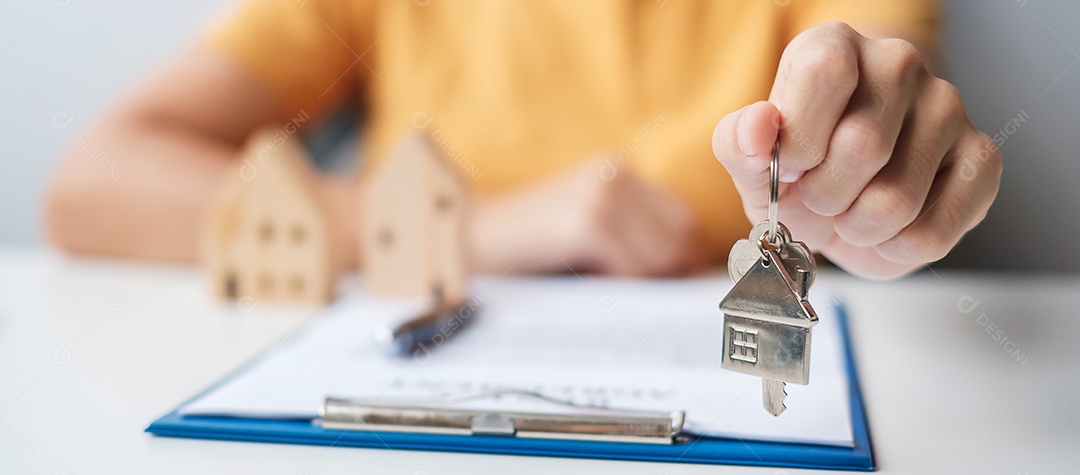 Mulher segurando a chave de casa durante a assinatura de documentos de contrato em casa. Contrato de contrato, imóveis, compra e venda e conceitos de seguros