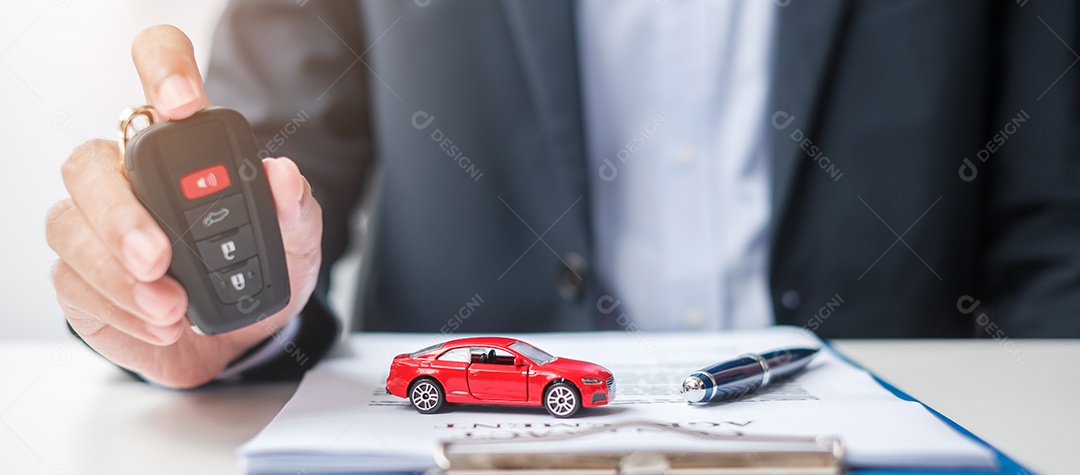 Mão de empresário segurando remoto sem chave com brinquedo de carro, caneta e documento de contrato. conceitos de compra e venda, seguro, aluguel e contrato