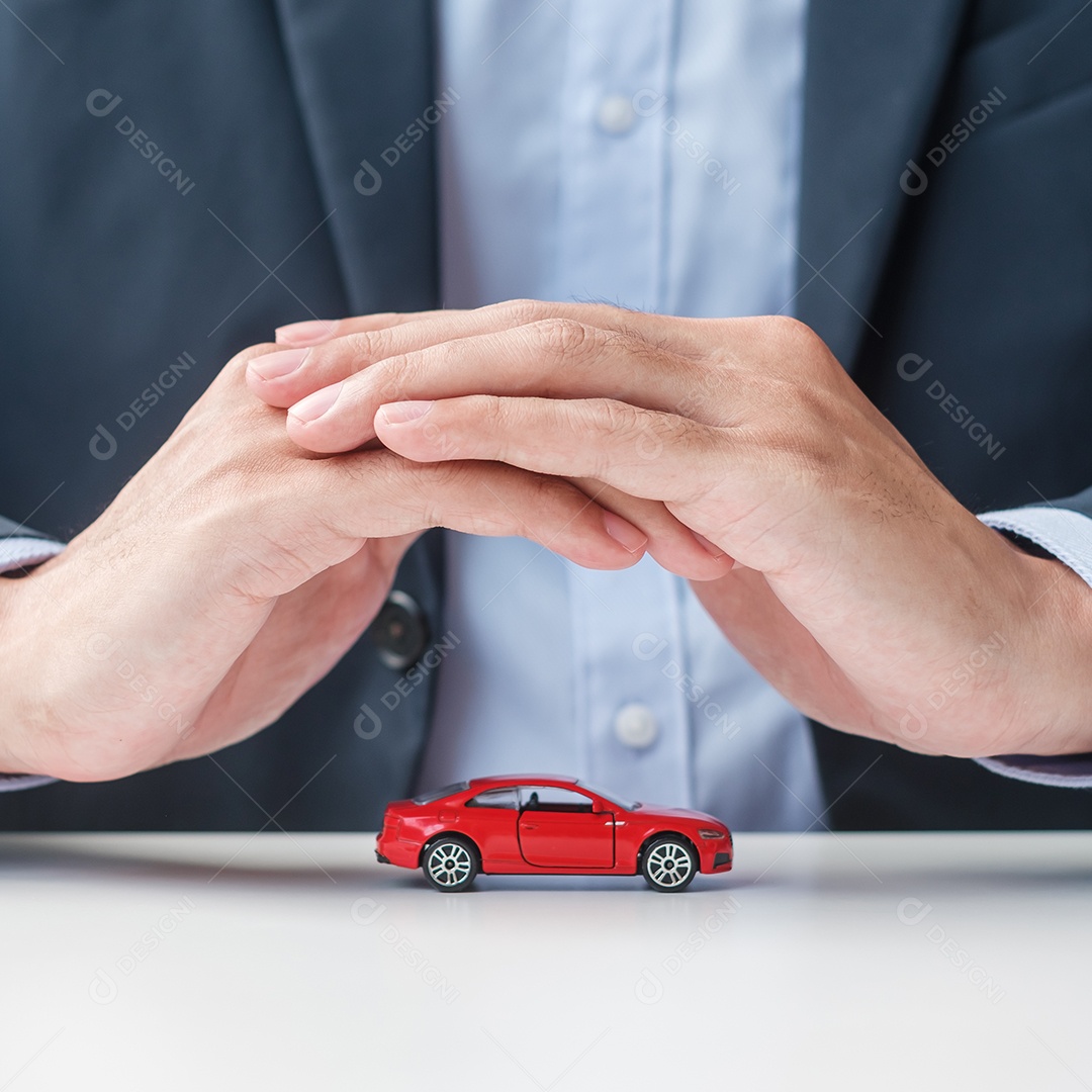 Businessman hand cover or protective red car toy on table. Car insurance, warranty, repair, financial, banking and money concept