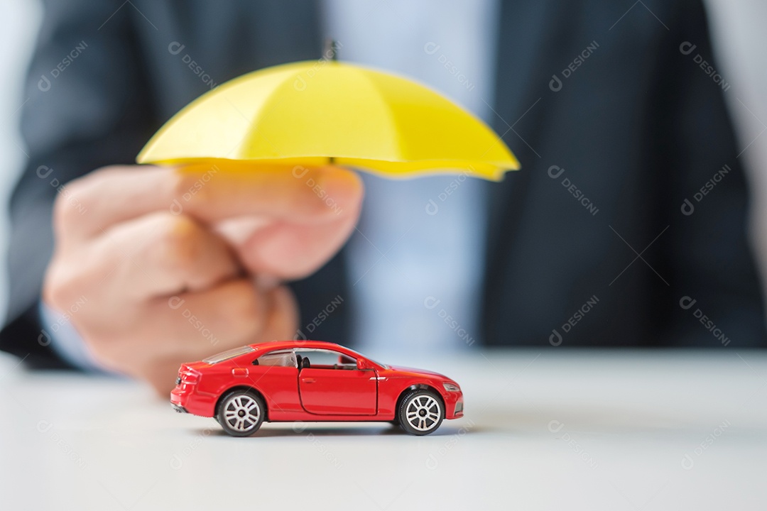 Mão de empresário segurando o guarda-chuva e cobrir o brinquedo do carro vermelho na mesa. Seguro automóvel, garantia, reparação, financeiro, bancário e conceito de dinheiro
