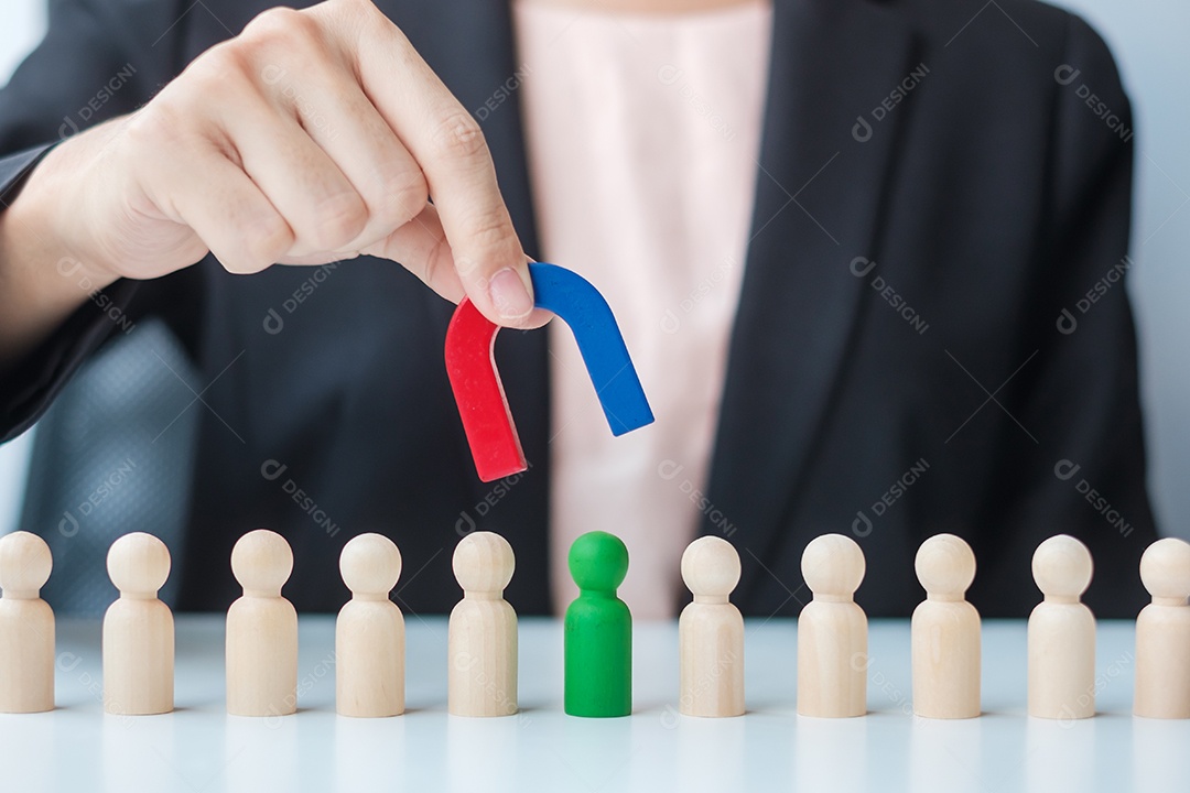 Mão de mulher de negócios segurando o ímã e puxando a figura de madeira do empregado da multidão. Negócios, gestão de recursos humanos, recrutamento, trabalho em equipe, estratégia, pessoas tóxicas e conceitos de liderança