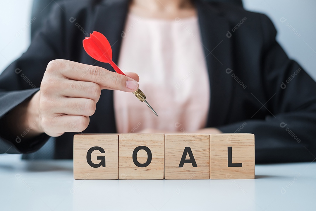 Mão segurando o dardo vermelho sobre o bloco de gol. alvo, objetivo, objetivo, liderança, conceito de negócios e marketing