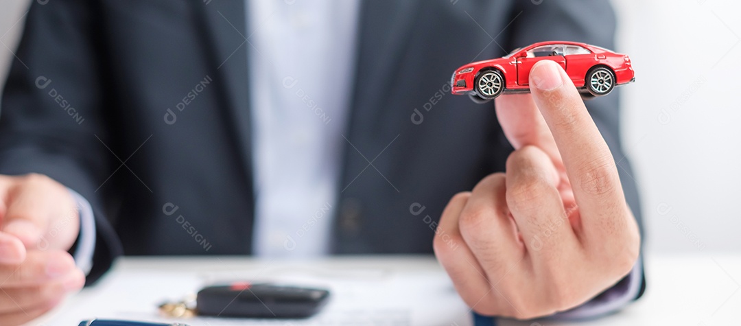 Mão de empresário segurando o brinquedo do carro vermelho com veículo sem chave, caneta e documento de contrato. conceitos de compra e venda, seguro, aluguel e contrato