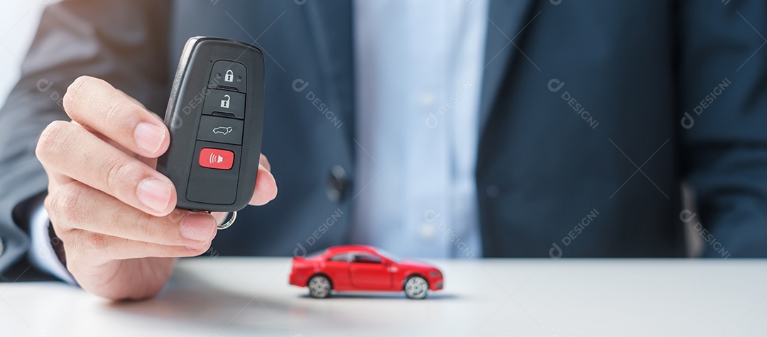 Mão de empresário segurando remoto sem chave com brinquedo de carro, caneta e documento de contrato. conceitos de compra e venda, seguro, aluguel e contrato