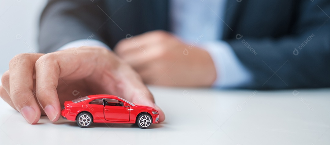 mão de empresário segurando o brinquedo do carro vermelho. Seguro de carro, garantia, aluguel, financeiro, novo e conceito de reparo