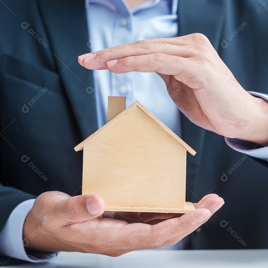 Modelo de casa de madeira da tampa da mão do empresário. conceitos imobiliários, seguros e imobiliários