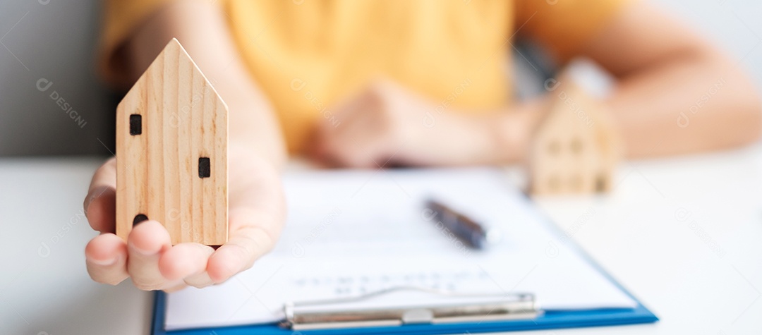 Mulher segurando o modelo de casa durante a assinatura de documentos de contrato em casa. Contrato de contrato, imóveis, compra e venda e conceitos de seguros