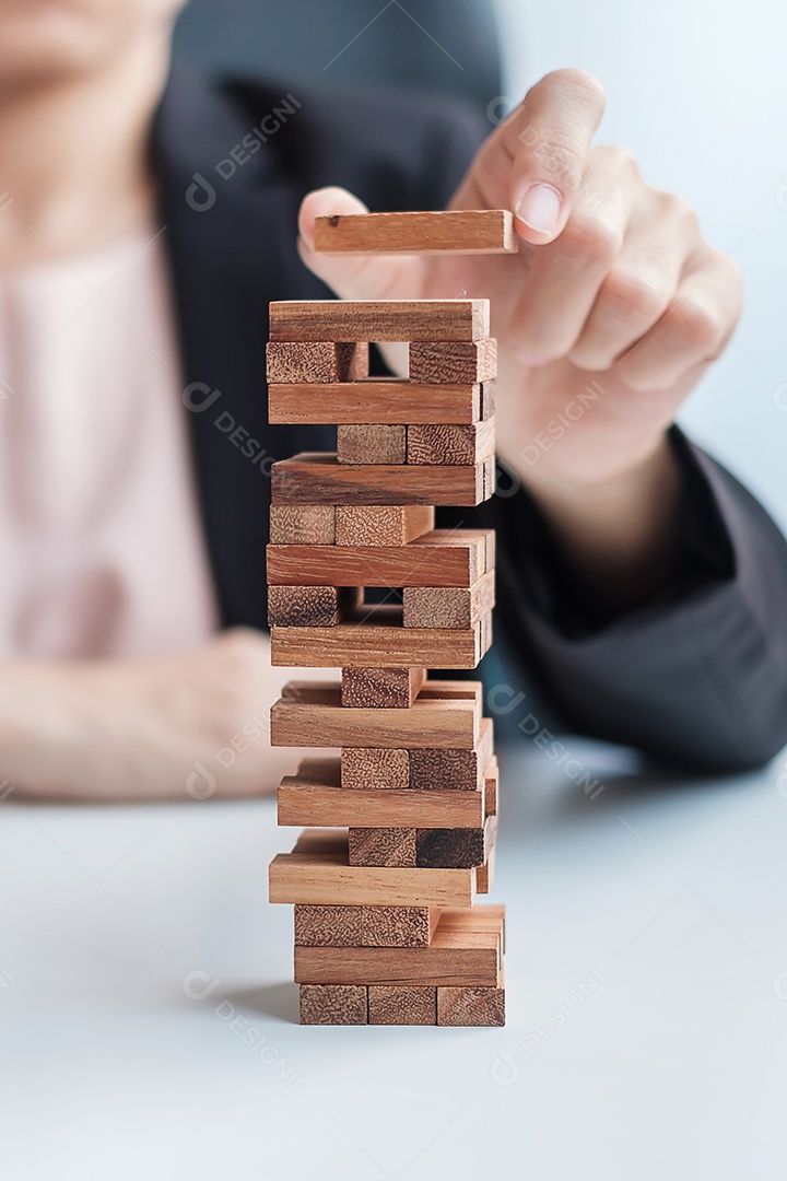 Mão de empresária colocando ou puxando o bloco de madeira na torre. Conceitos de planejamento de negócios, gerenciamento de riscos, solução e estratégia