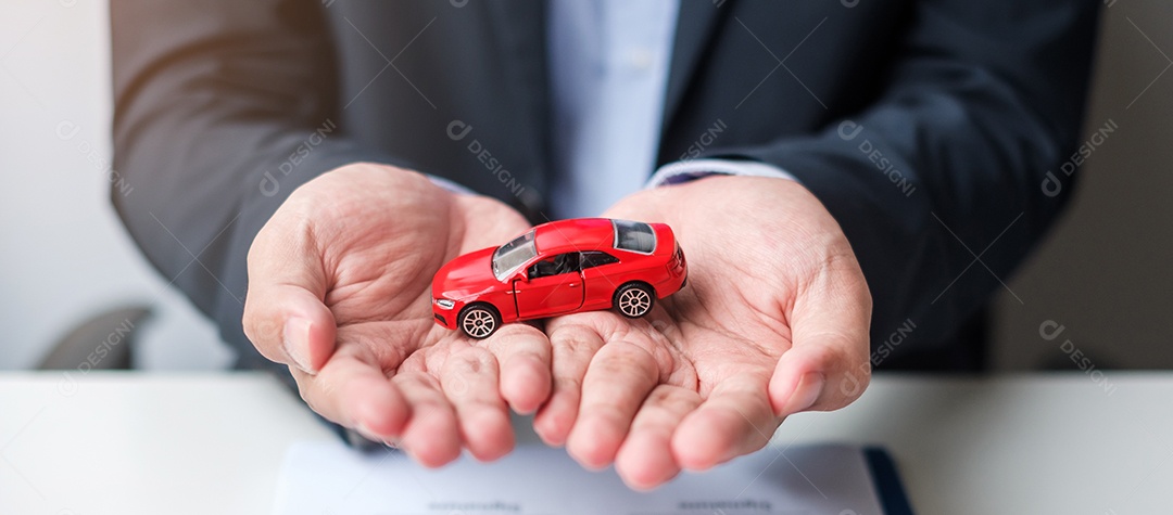 Mão de empresário segurando o brinquedo do carro vermelho com veículo sem chave, caneta e documento de contrato. conceitos de compra e venda, seguro, aluguel e contrato