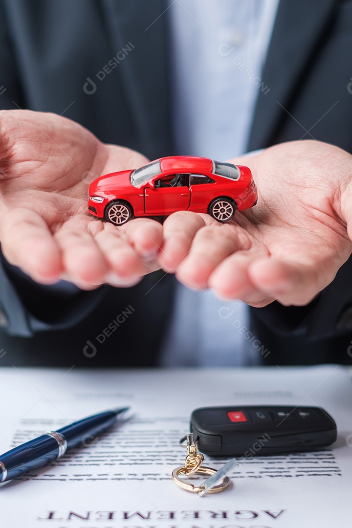 Mão de empresário segurando o brinquedo do carro vermelho com veículo sem chave, caneta e documento de contrato. conceitos de compra e venda, seguro, aluguel e contrato