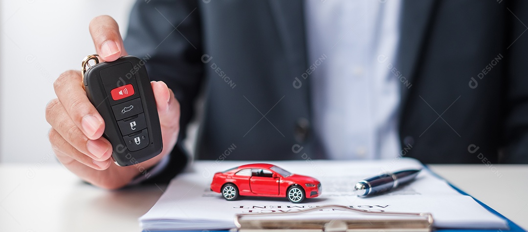 Mão de empresário segurando remoto sem chave com brinquedo de carro, caneta e documento de contrato. conceitos de compra e venda, seguro, aluguel e contrato