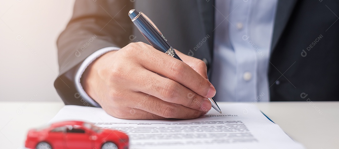 Mão de empresário segurando o brinquedo do carro vermelho com veículo sem chave, caneta e documento de contrato. conceitos de compra e venda, seguro, aluguel e contrato